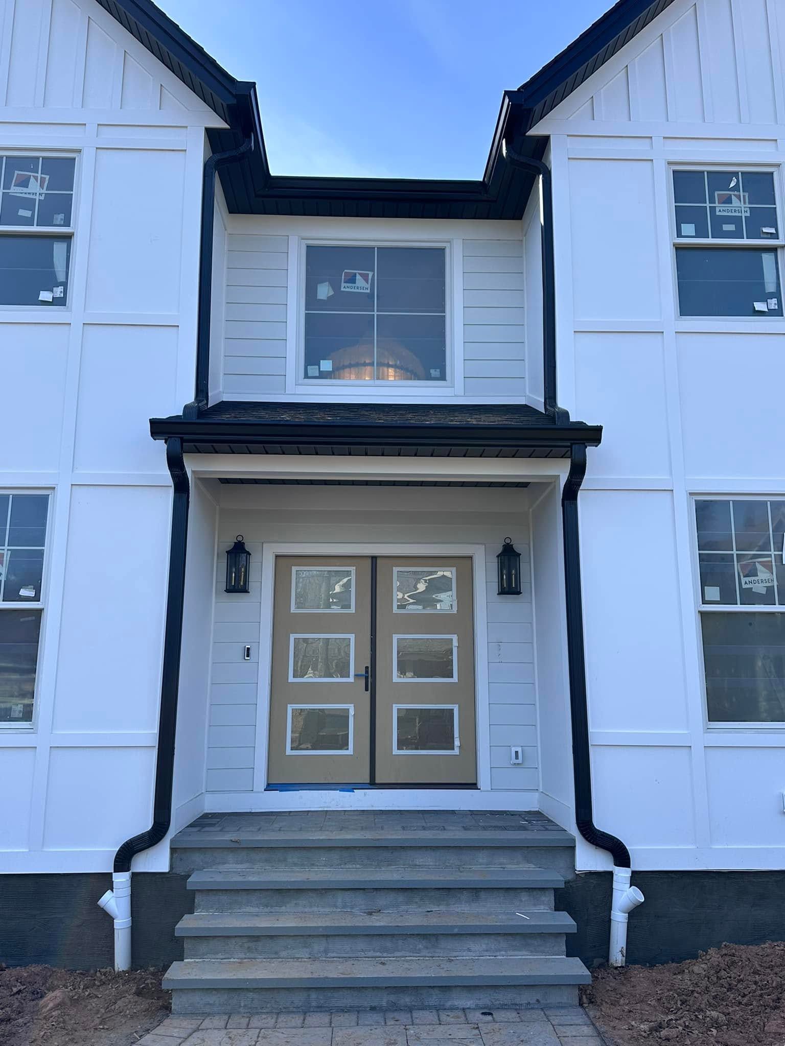 Front entrance of a white house with gray double doors, steps, and black trim