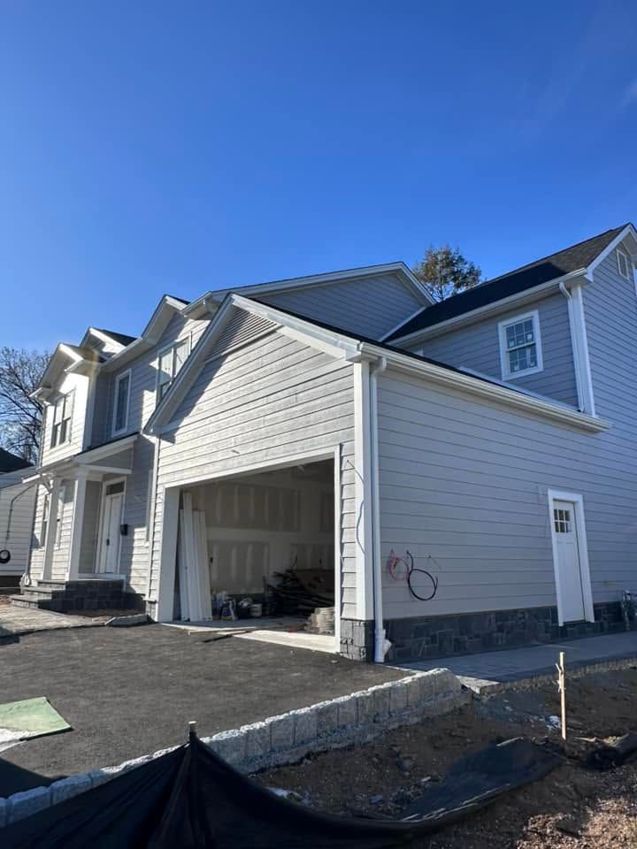 New suburban house with attached garage, white siding, and blue sky