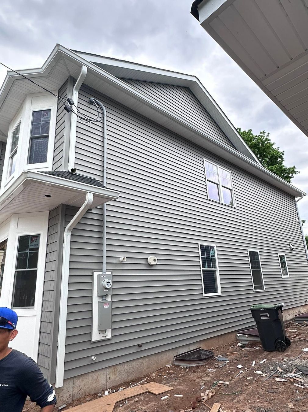 Gray-sided house exterior with white trim and two-story porch under overcast sky