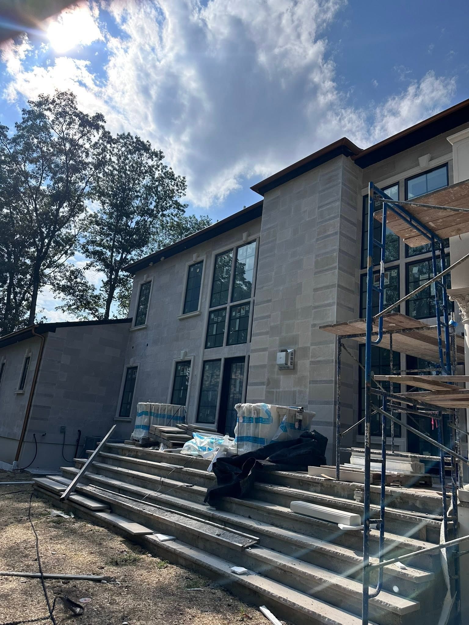 Front steps of a modern house under construction with scaffolding and building materials.