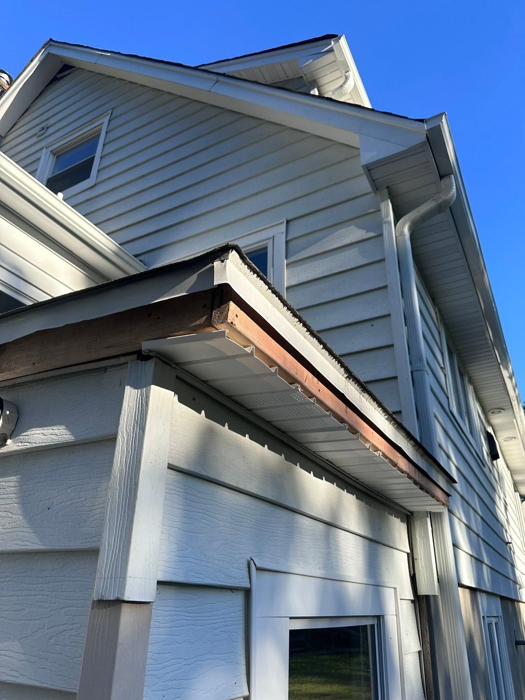 Close-up of a gray house exterior with white trim and blue sky above