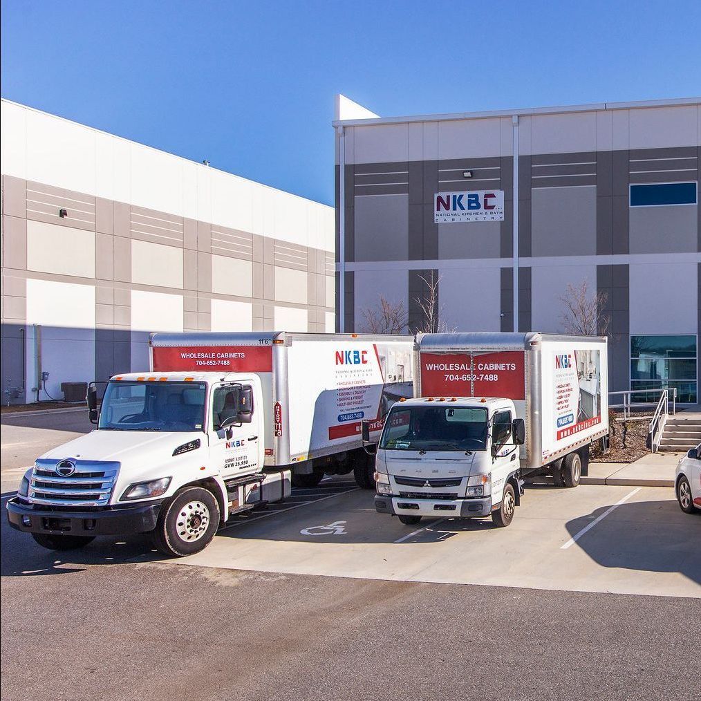 Several trucks are parked in front of a building that says nkbc