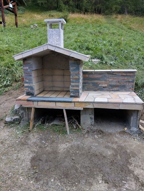Une cheminée en briques avec une cheminée se trouve au milieu d'un champ herbeux.