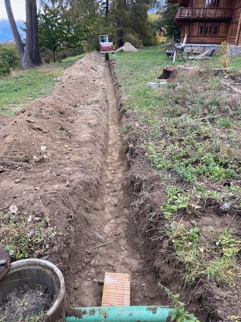 Une tranchée est creusée dans la terre devant une maison.