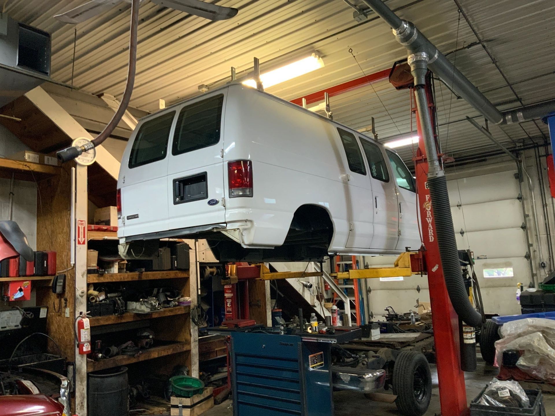 A white van is sitting on a lift in a garage. | North County Service Center