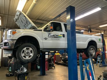 A white truck is sitting on a lift in a garage. | North County Service Center