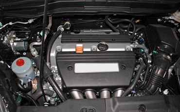 A close up of a car engine with the hood open. | North County Service Center
