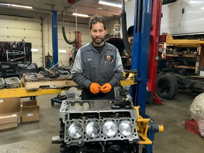 A man is standing in front of a engine in a garage. | North County Service Center