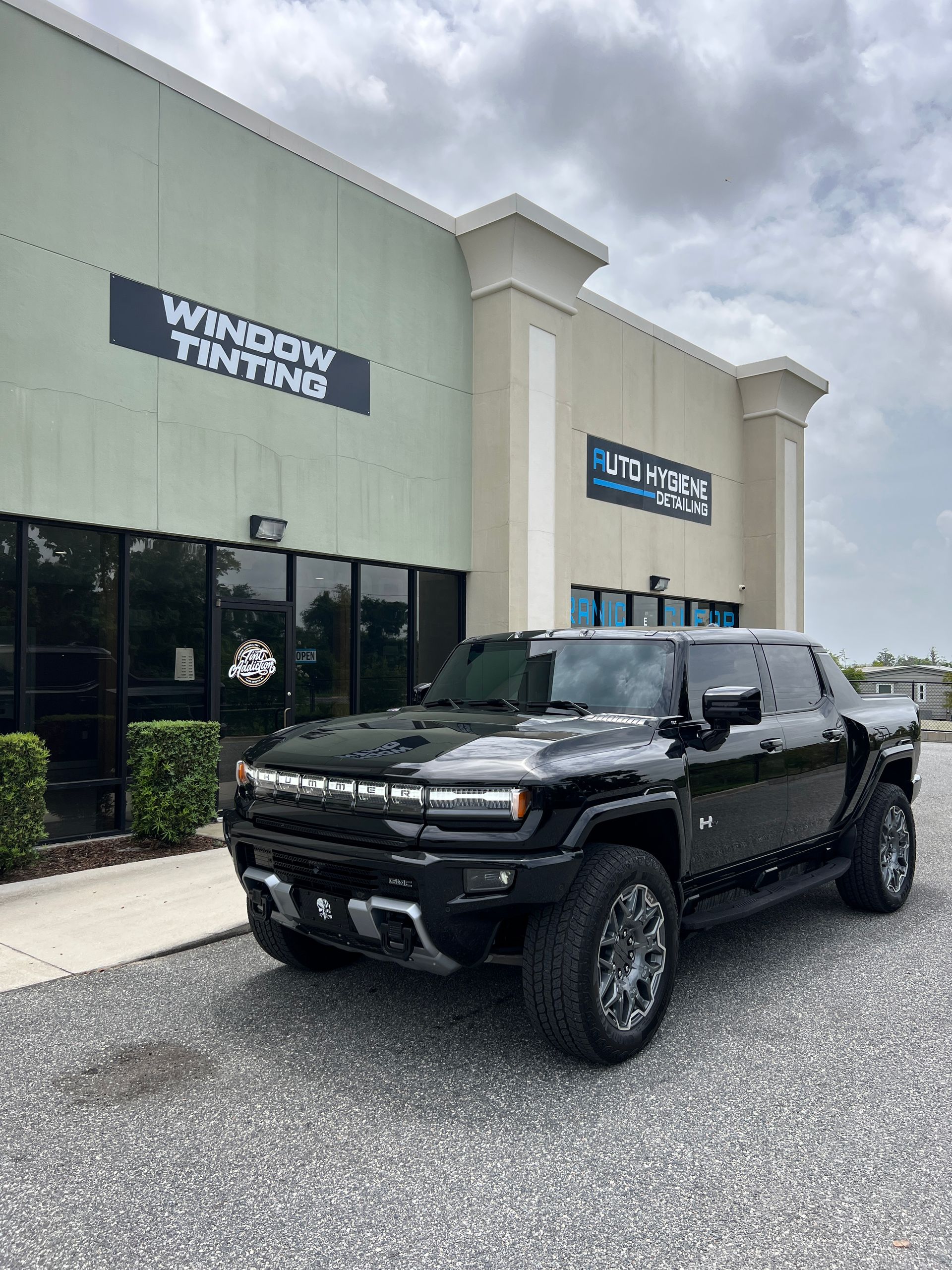 Black Hummer EV parked outside a window tinting business.