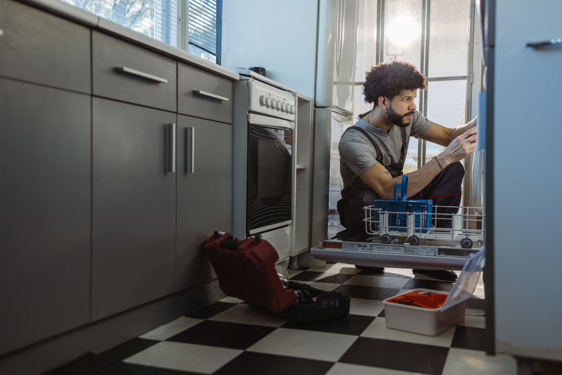 Technician repairing dishwasher in modern kitchen providing quick sameday appliance repair service.