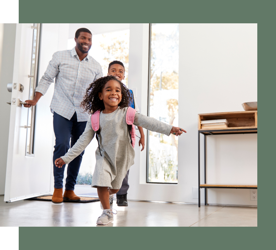 A man and two children are walking through a doorway.