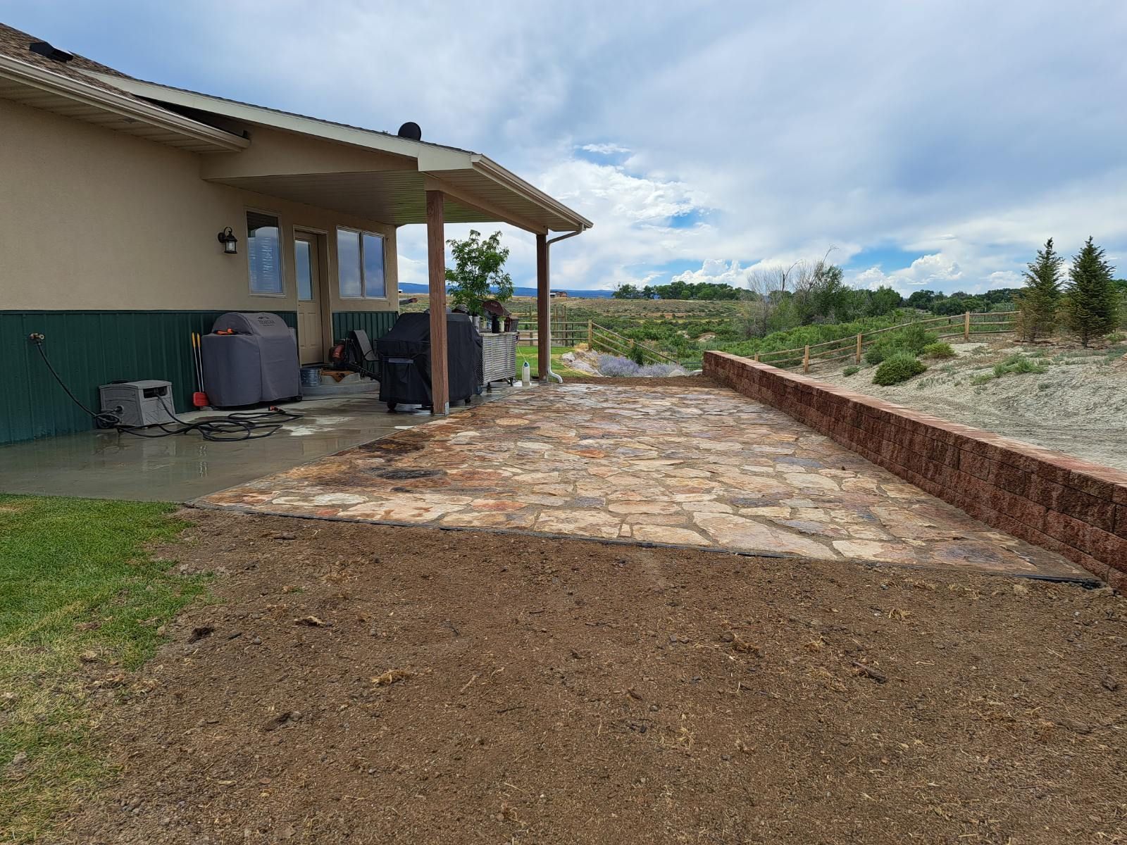 Backyard patio with stone paving and a retaining wall.