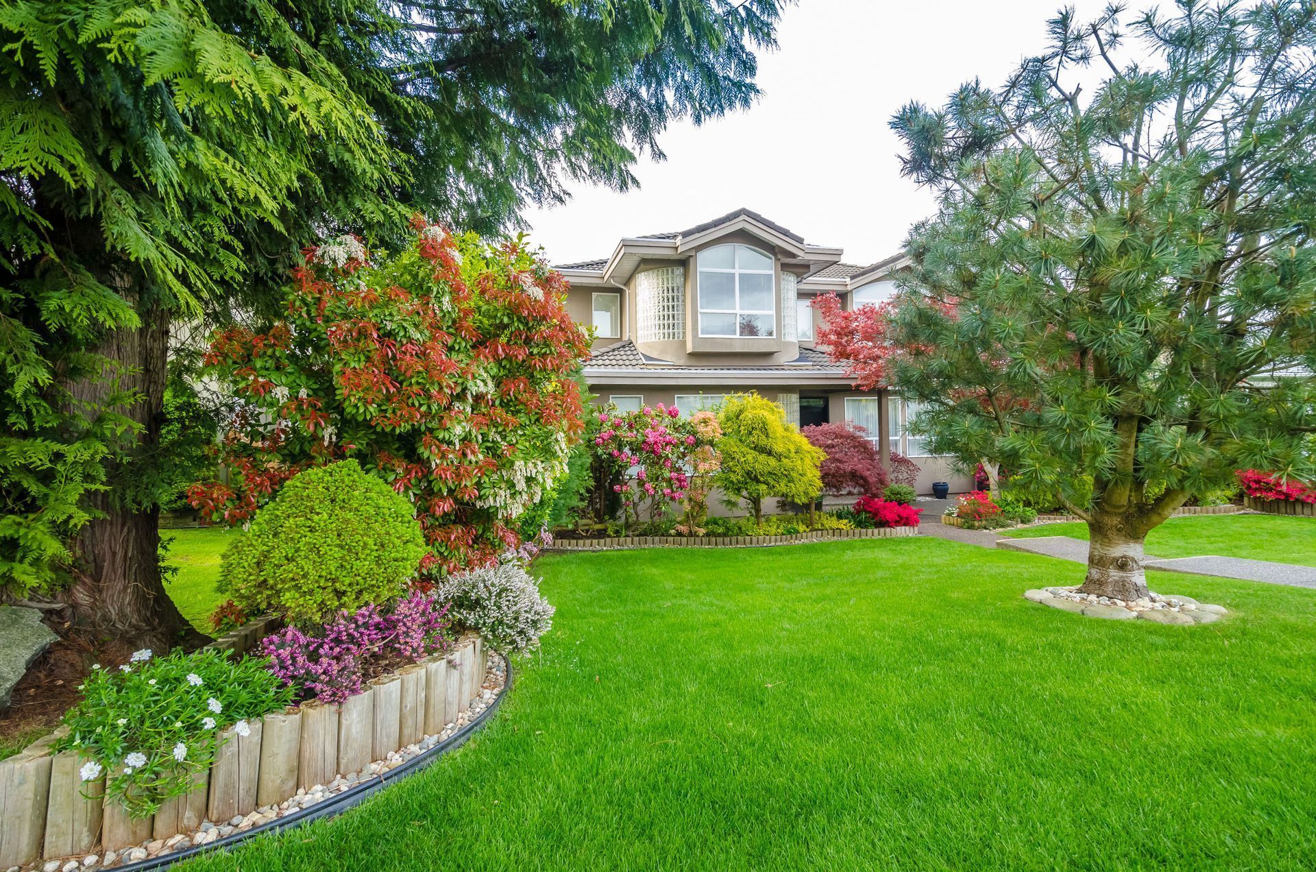 House with green lawn and colorful flower beds.