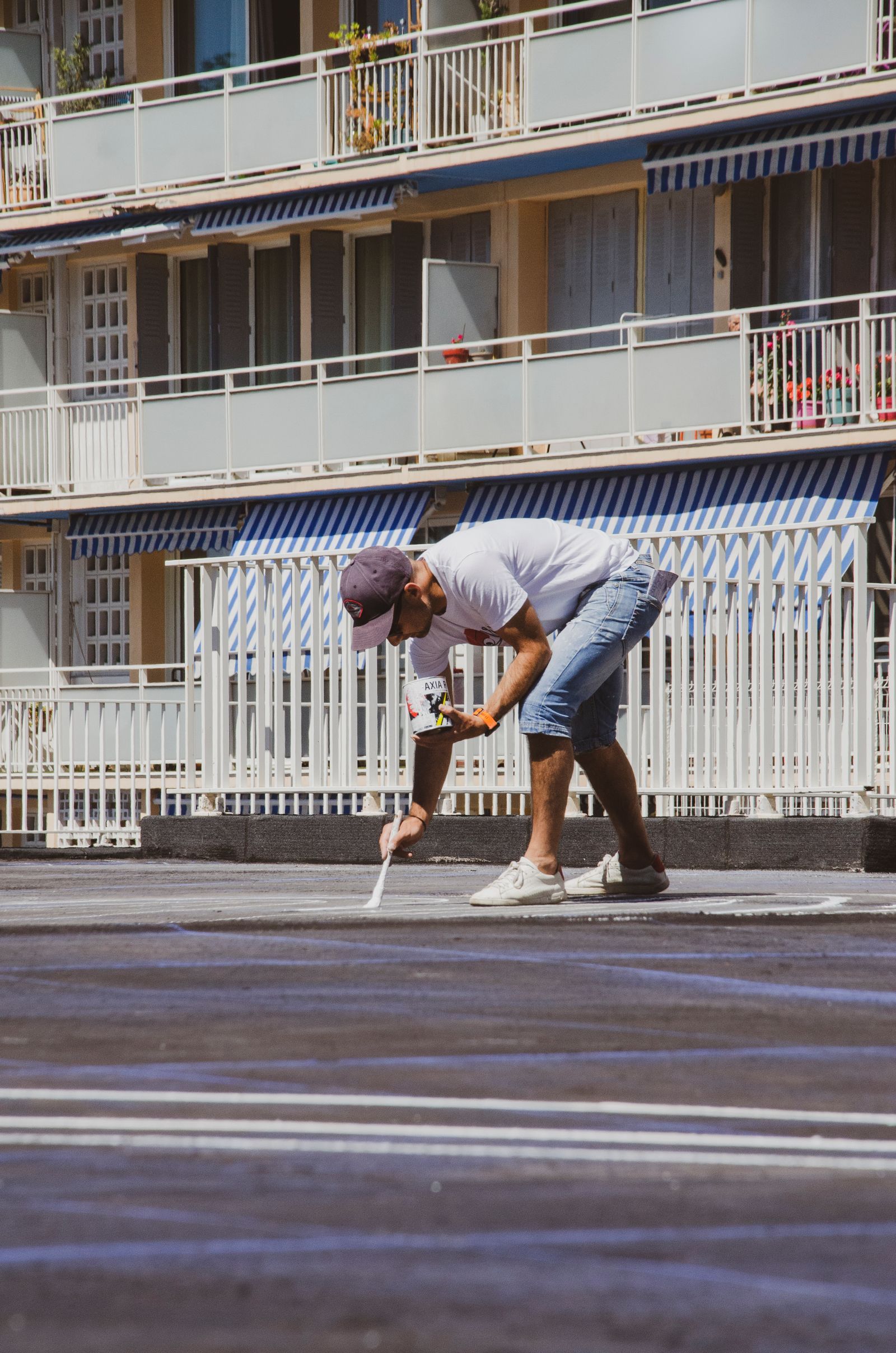 Worker painting parking lot lines on asphalt