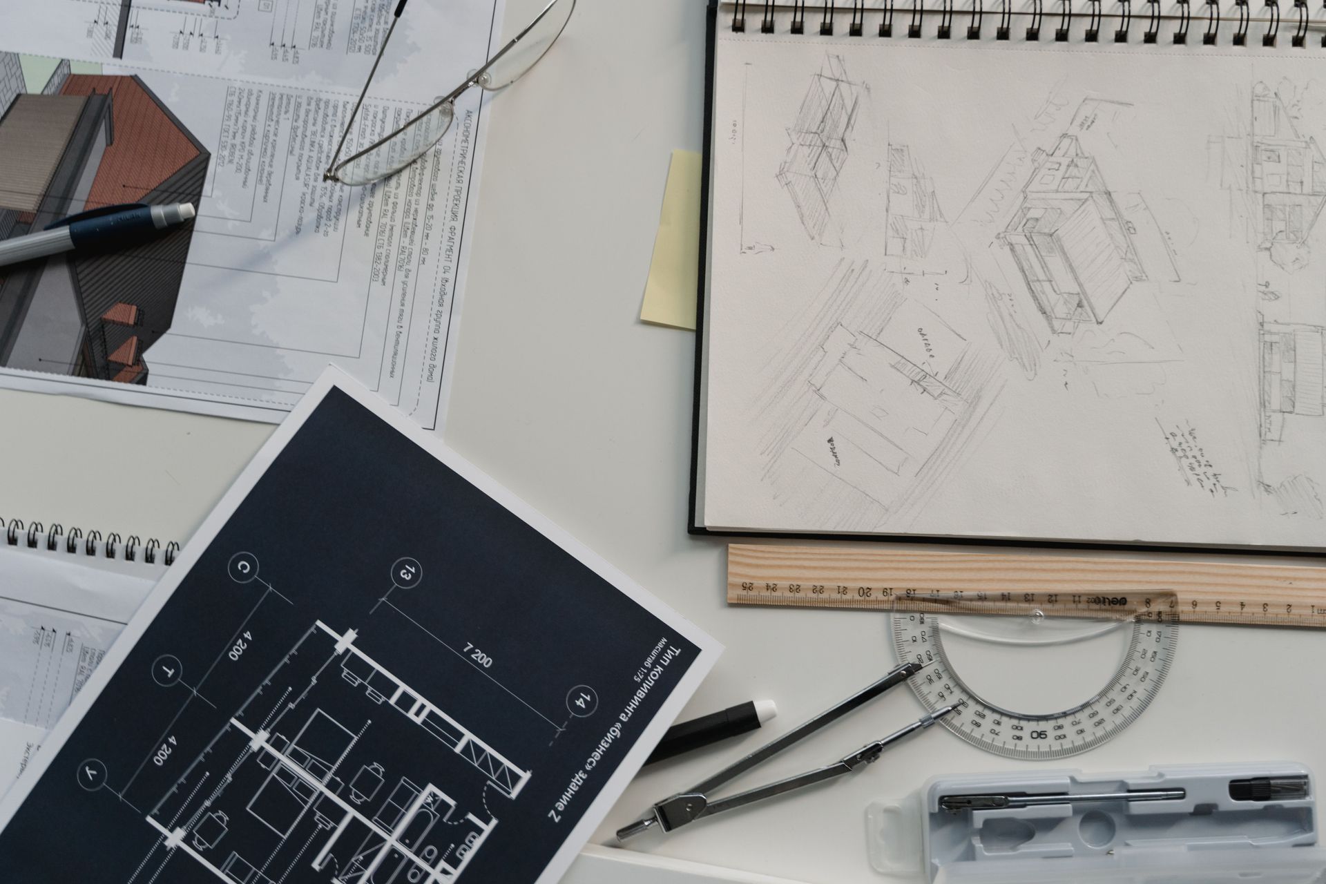 Architect’s desk with blueprint, pencil, ruler, compass, and sketchbook on a white work surface