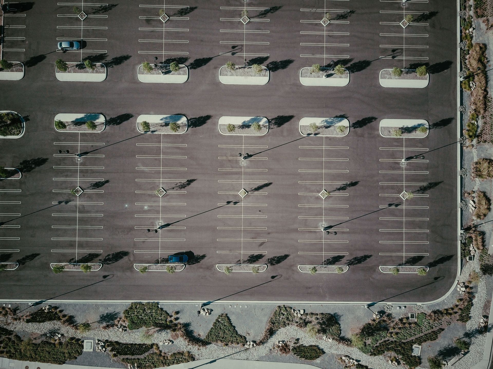 Aerial view of asphalt parking lot with painted white stall lines