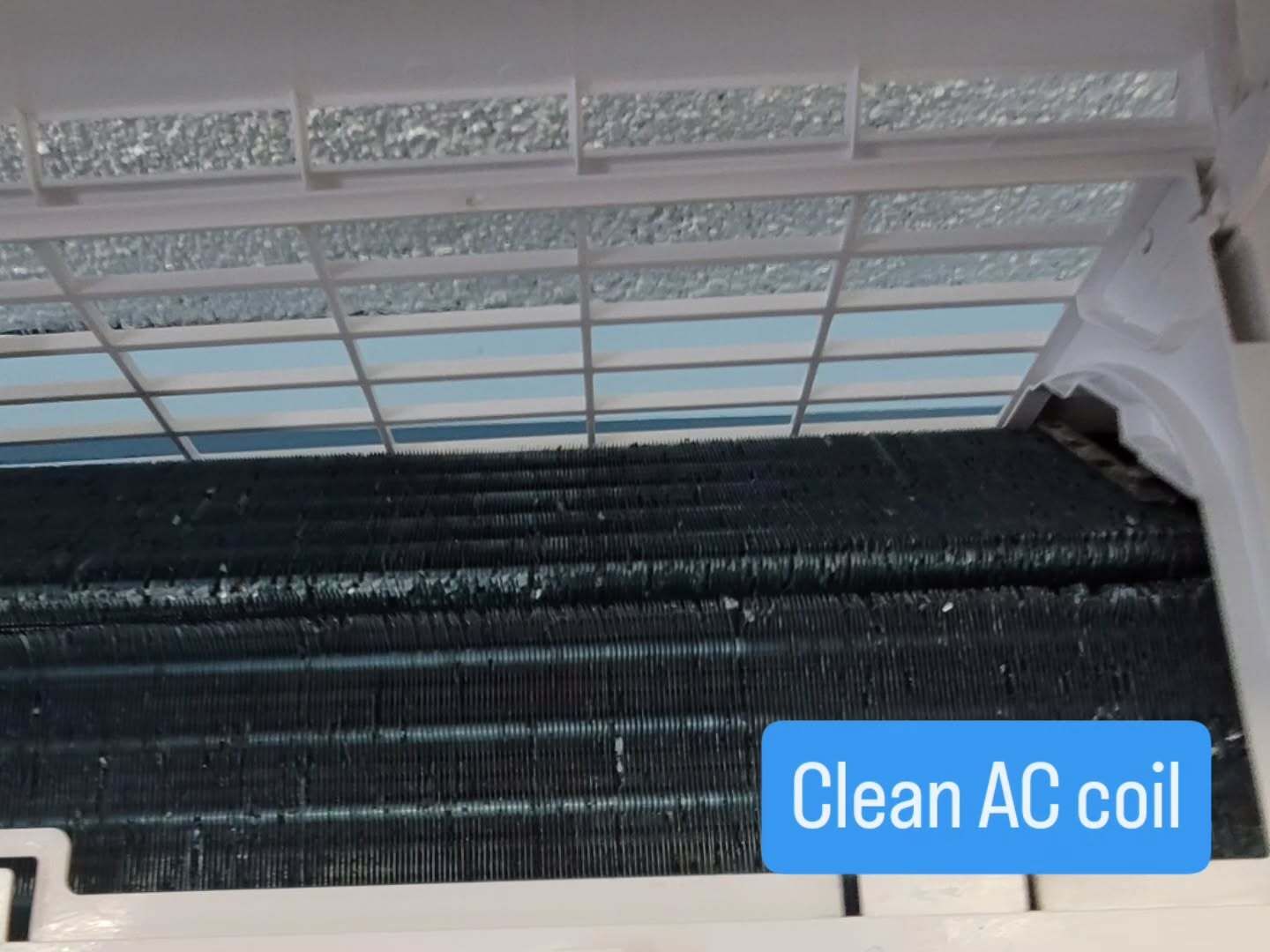 Clean AC coil behind a white grille with a blue “Clean AC coil” label