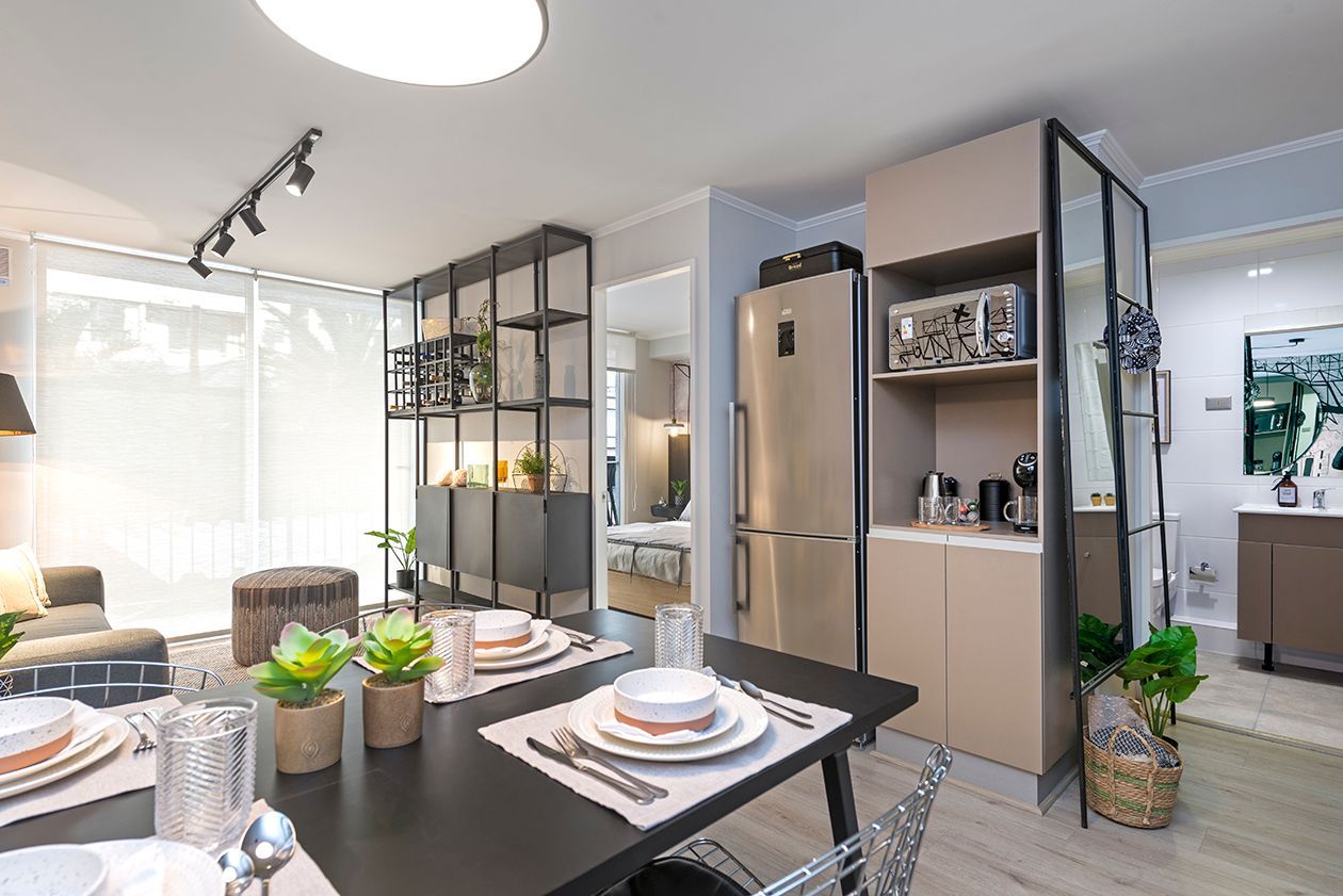 Cocina y comedor modernos con mesa negra, nevera de acero inoxidable y armarios de cristal.