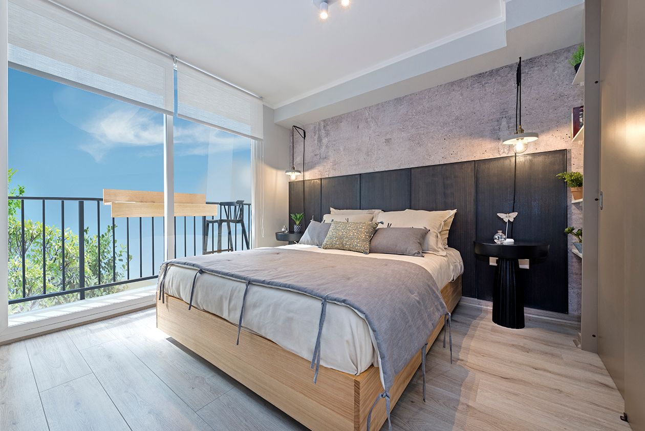 Habitación luminosa y moderna con cama, grandes ventanales y balcón con vistas al océano.