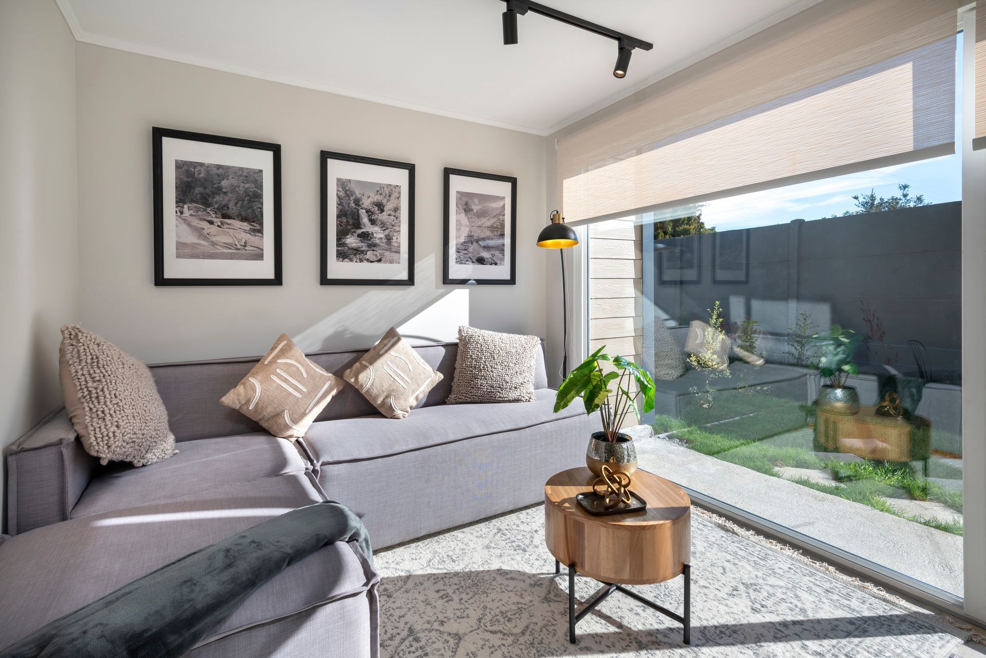 Salón luminoso y moderno con sofá gris, cuadros enmarcados.