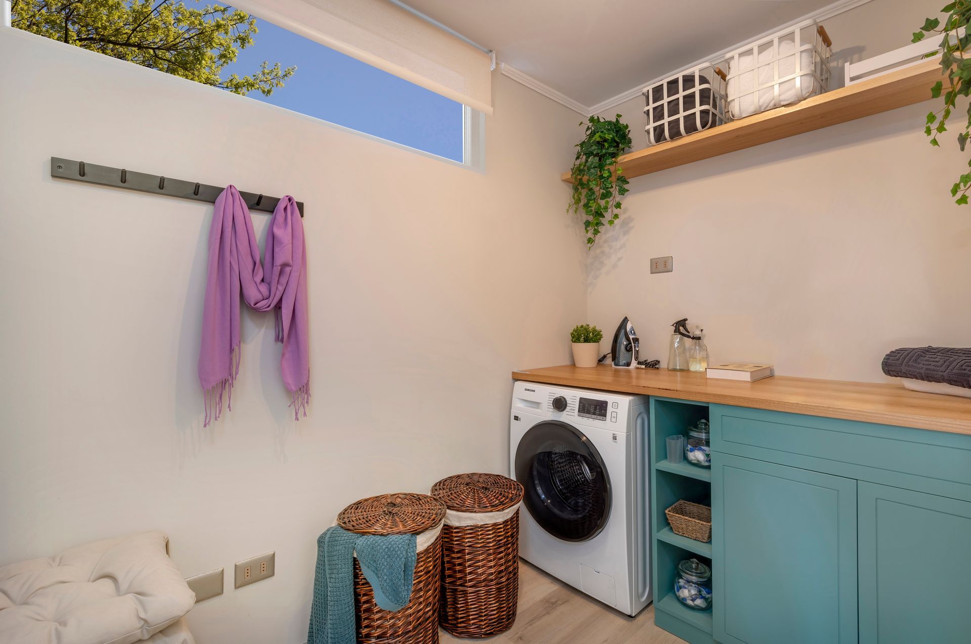 Rincón de lavandería compacto con armarios color menta, encimera de madera, estantes abiertos.