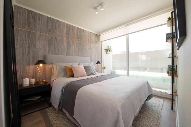 Dormitorio moderno con una cama bien hecha, pared revestida de madera y grandes puertas correderas de cristal.