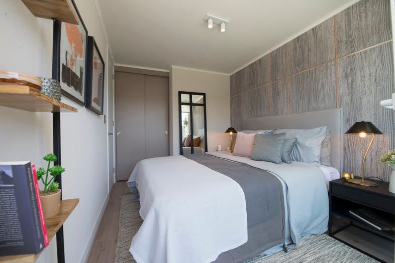 Dormitorio moderno con una cama bien hecha, pared decorativa gris, lámpara de noche y estantes de pared.