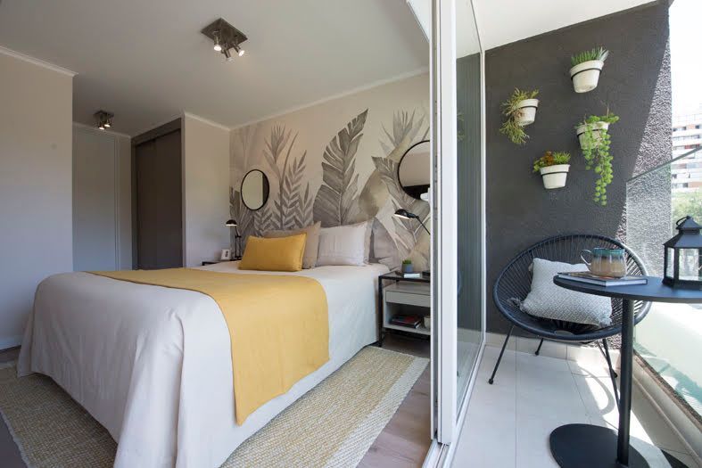 Habitación compacta con cama, decoración mural con motivos vegetales.