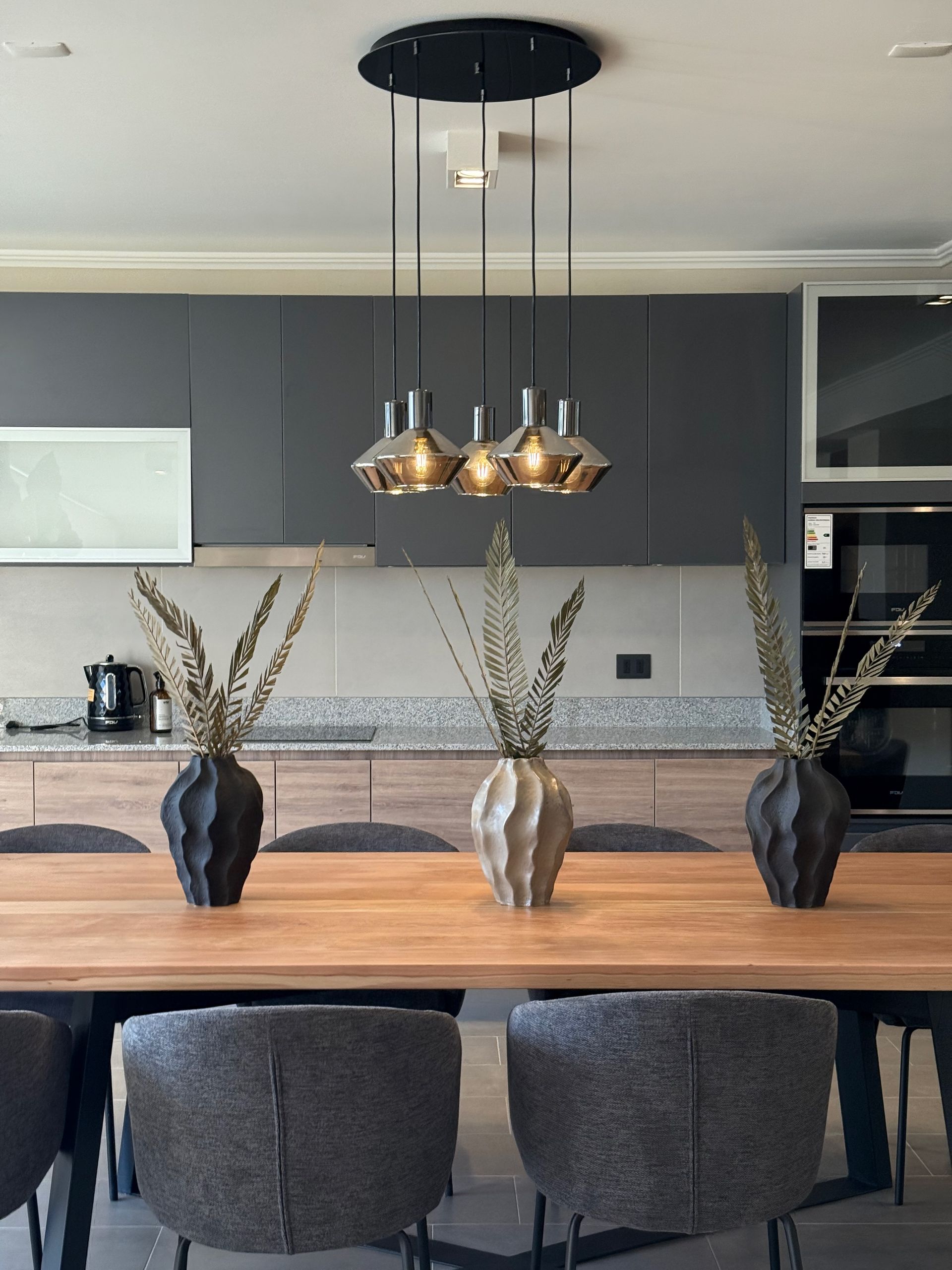 Mesa de comedor moderna con tablero de madera y patas de metal negro sobre fondo blanco.