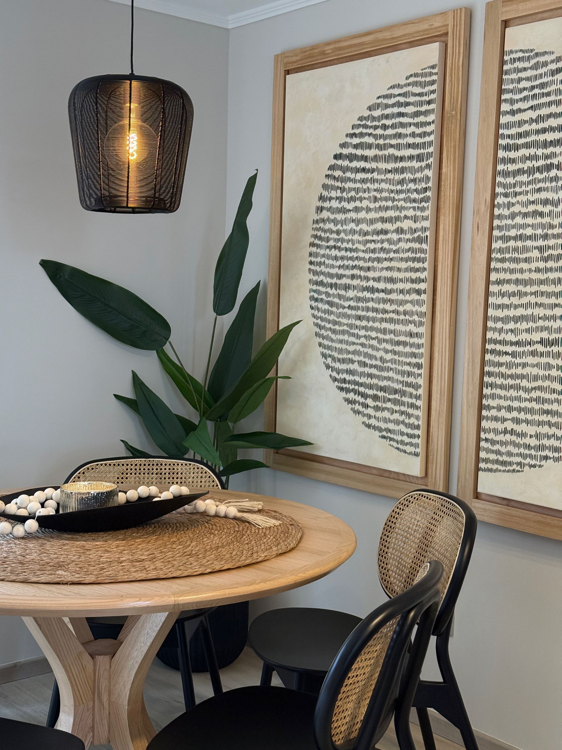 Acogedor rincón de comedor con sillas de mimbre, mesa redonda de madera, lámpara colgante.