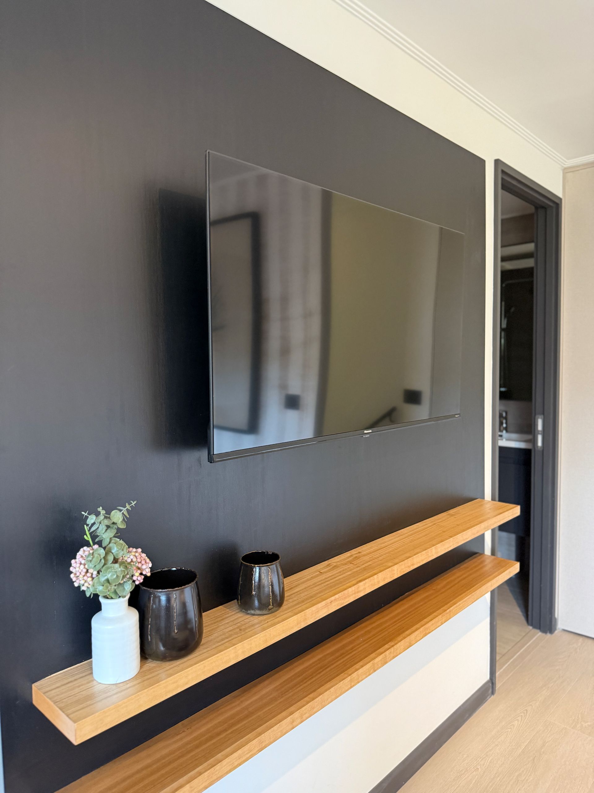 Pasillo moderno con televisor montado en la pared sobre una consola de madera.
