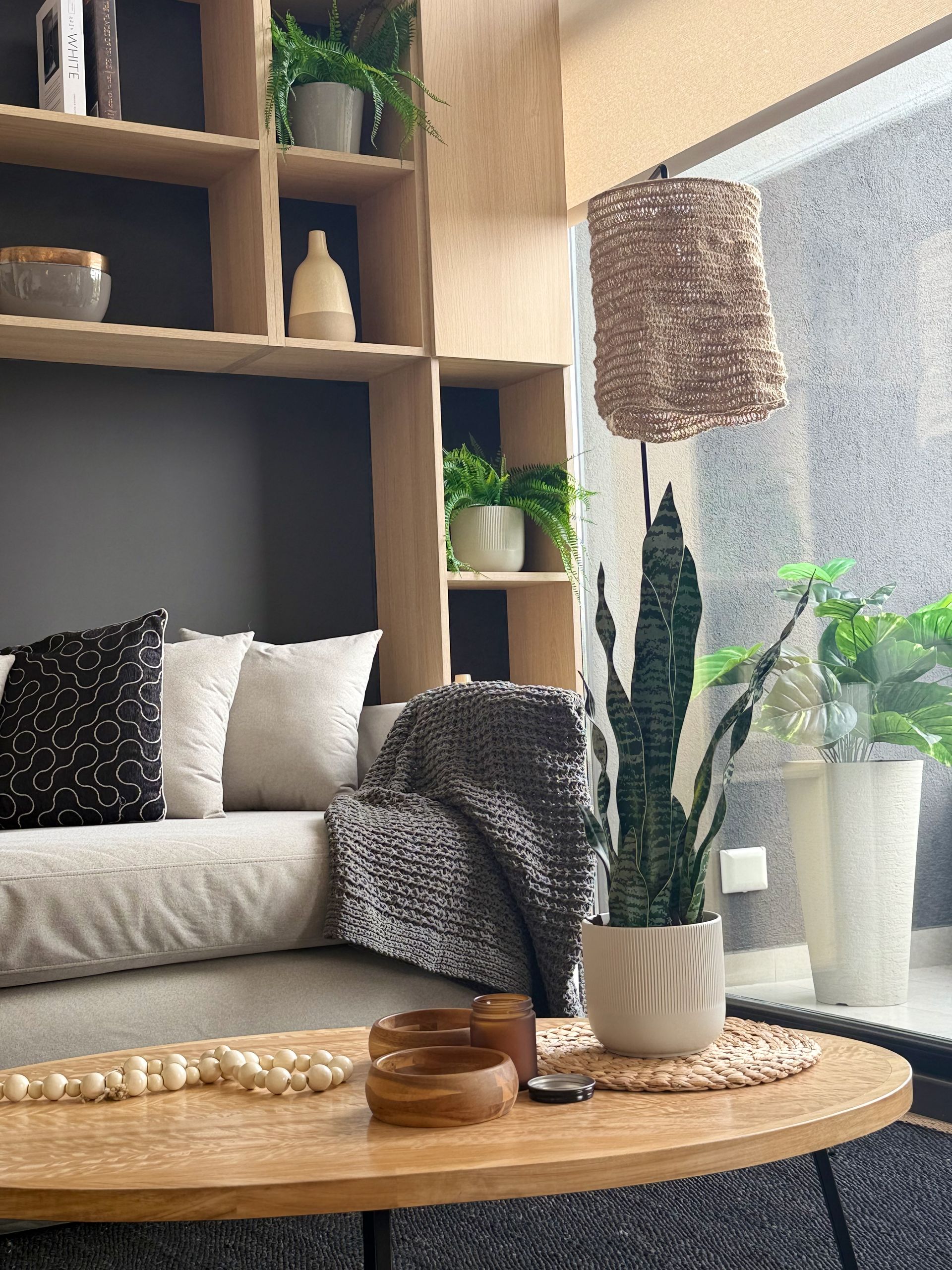 Acogedora sala de estar con sofá beige, mesa de centro de madera, plantas y luz natural suave.