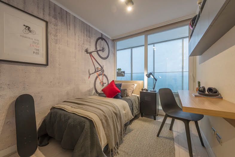 Habitación pequeña y moderna con cama individual, escritorio, silla, cuadro de bicicleta en la pared.