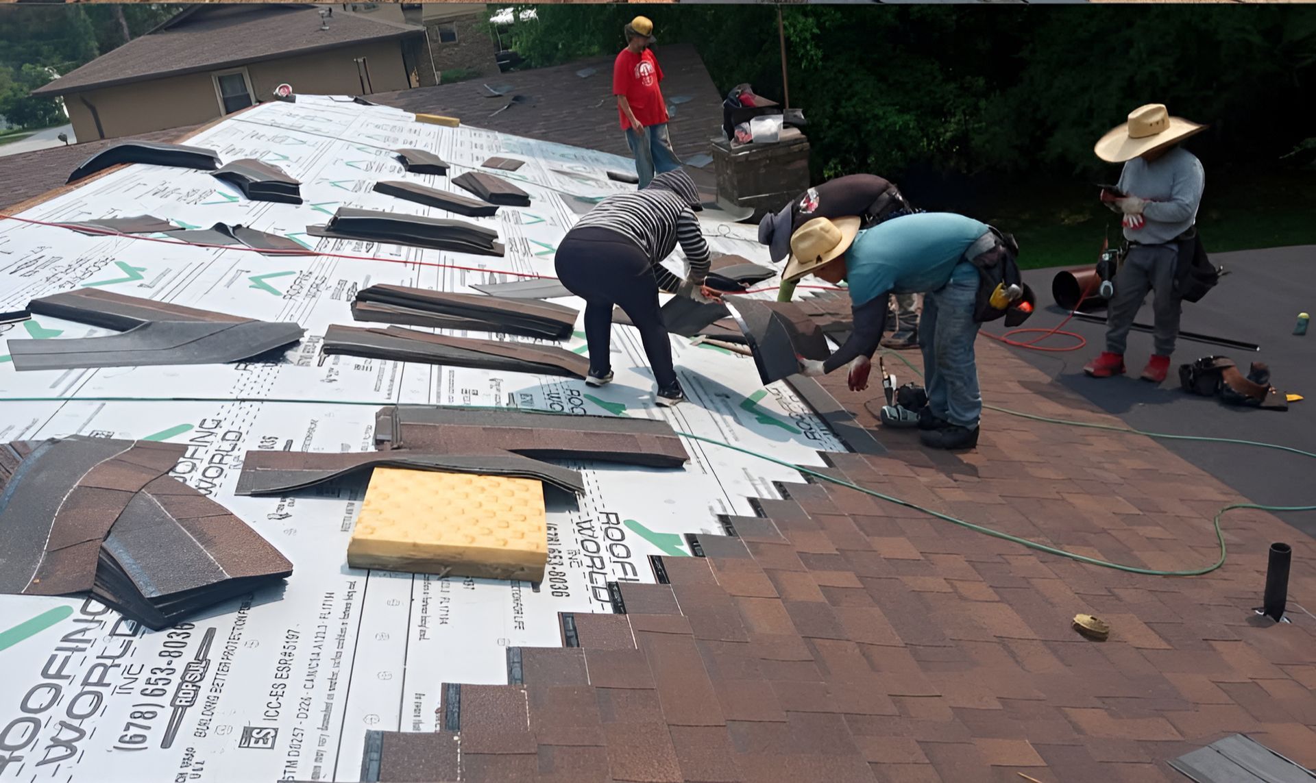 Workers installing roofing on a sloped roof, with white underlayment and brown shingles in progress.