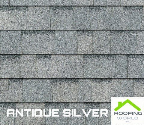 Close-up of gray shingle roof samples labeled “Antique Silver” with a roofing world logo