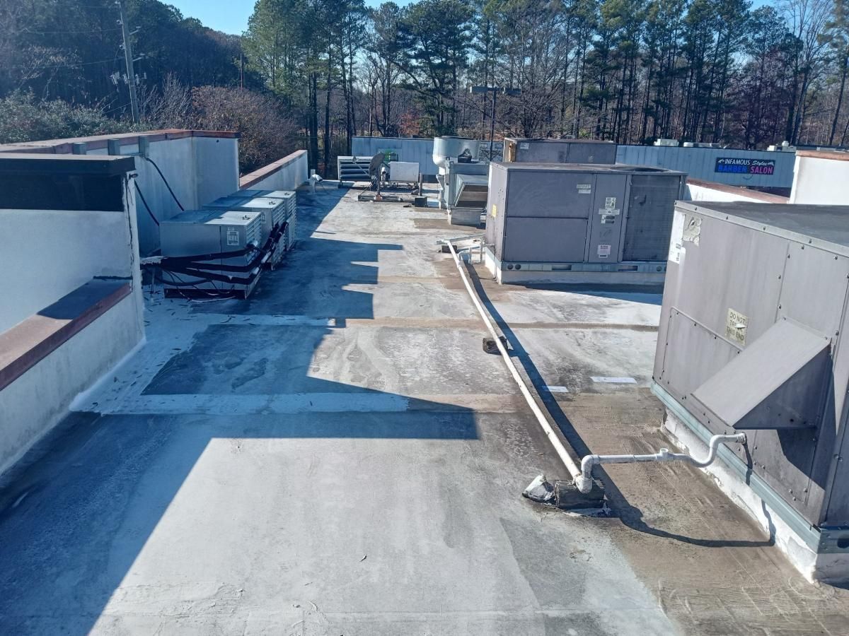 Rooftop with HVAC units, vents, and ductwork on a flat roof under a clear sky.