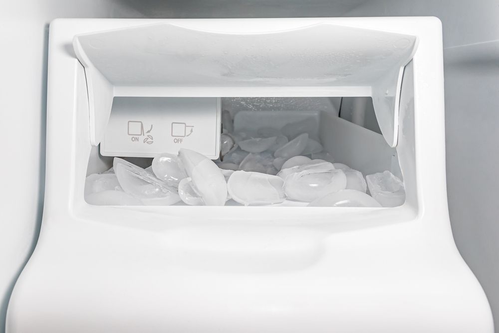 White refrigerator ice bin filled with ice cubes, with a small instruction panel on the left.