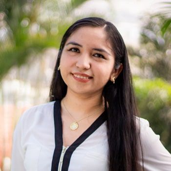 Una mujer de pelo largo viste una camisa blanca y una corbata negra.
