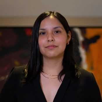Una mujer con traje negro está parada frente a un cuadro.