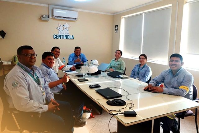 Un grupo de personas están sentadas alrededor de una mesa frente a un cartel que dice Centinela.