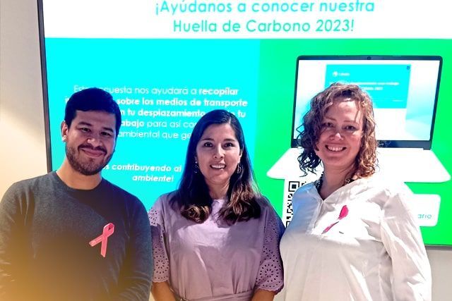 Tres personas posan para una fotografía frente a un ordenador portátil.
