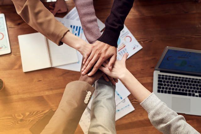 Un grupo de personas junta las manos sobre una mesa de madera.