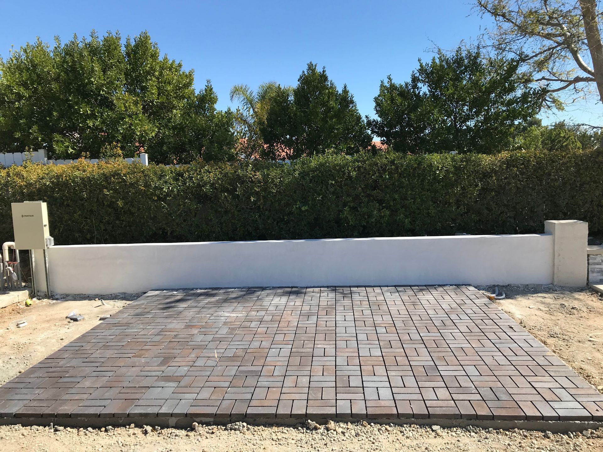 A brick walkway with a white wall in the background