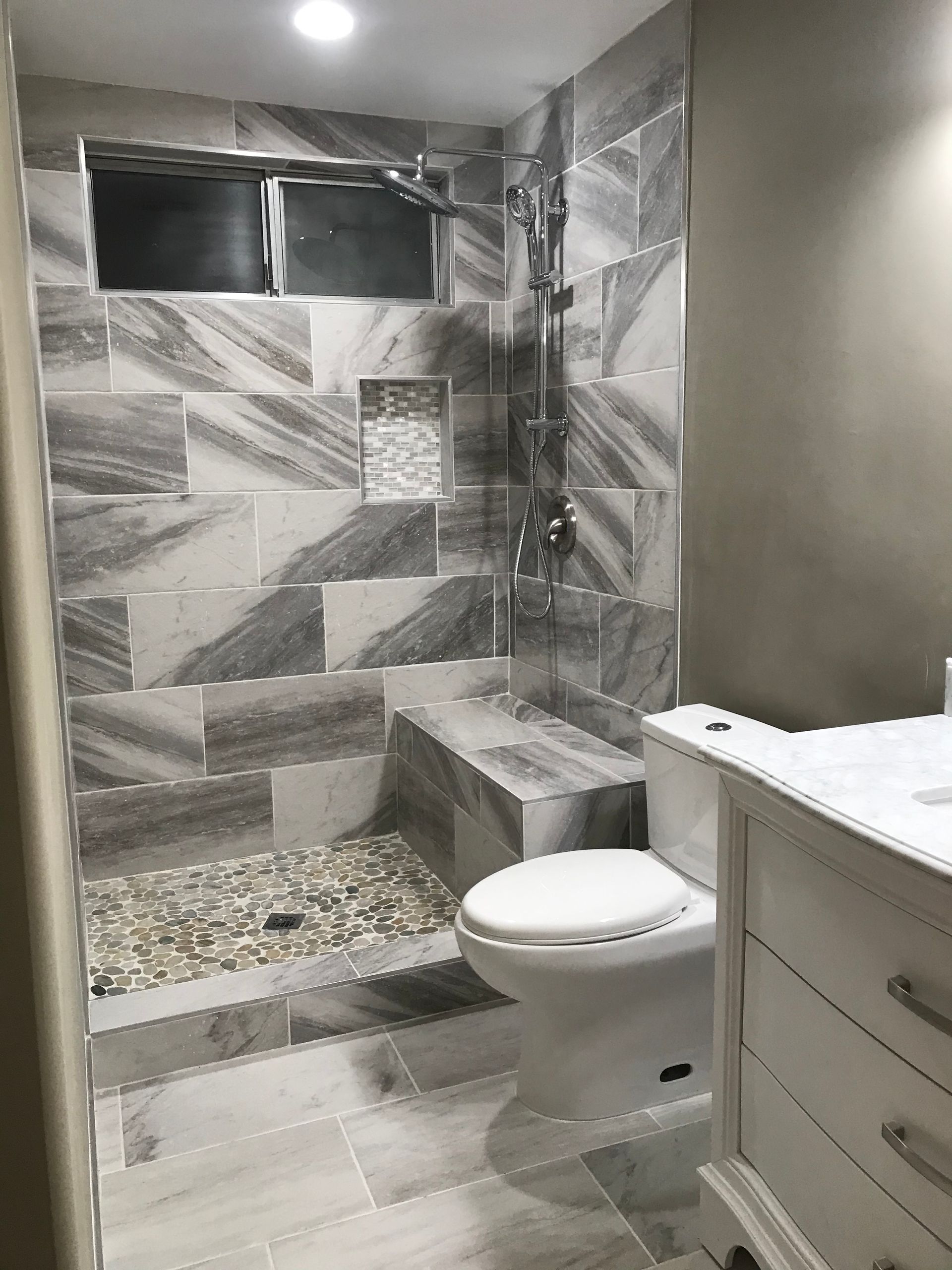 A bathroom with a toilet , sink and shower.