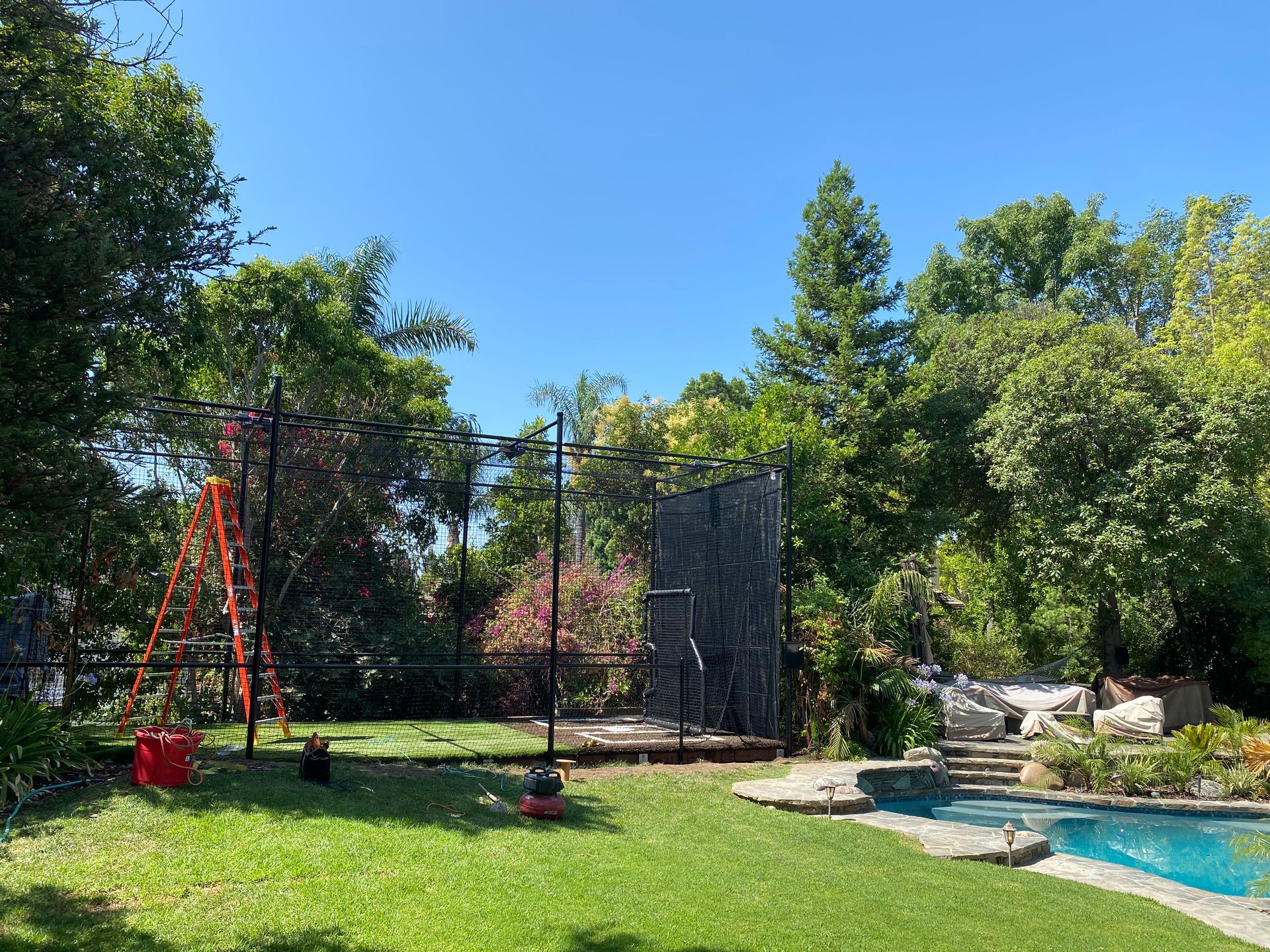 A backyard with a swimming pool and a climbing wall.
