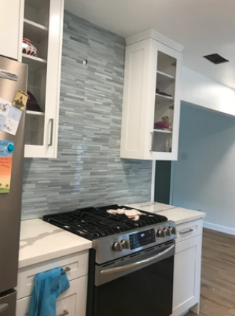 A kitchen with white cabinets and a stove top oven