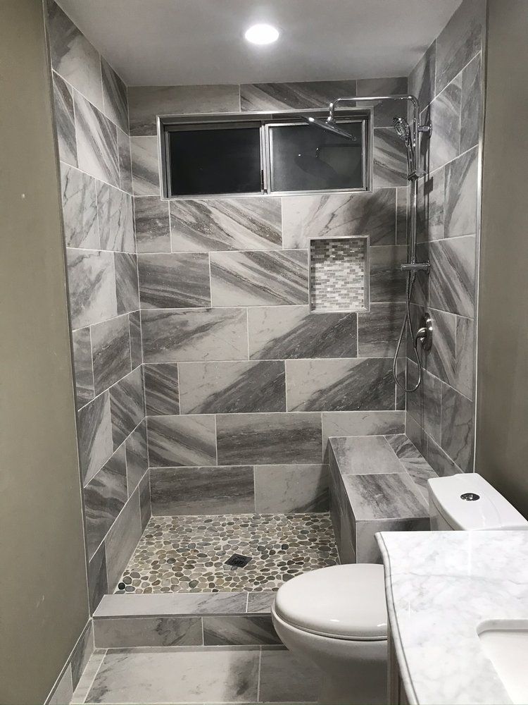 A bathroom with a toilet , sink and mirror.