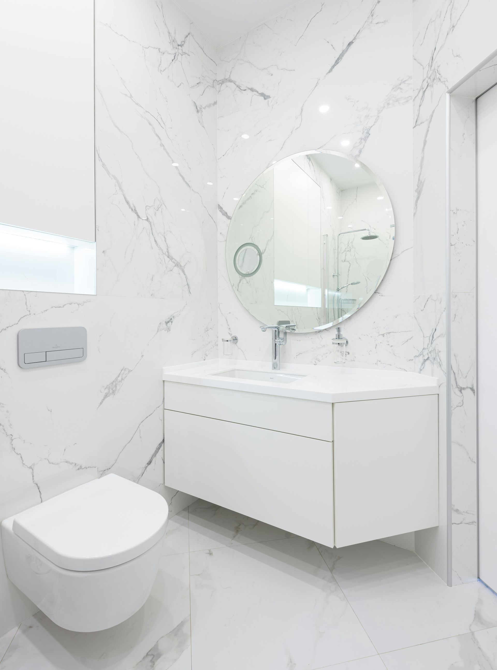 A bathroom with a toilet , sink and mirror.