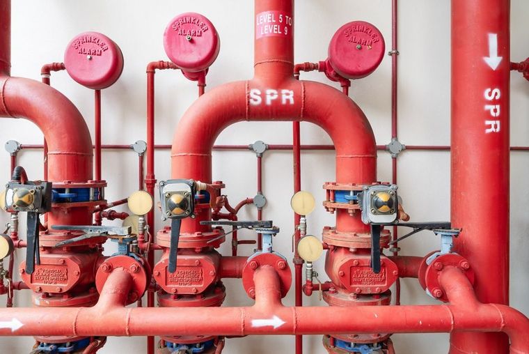 Red fire sprinkler pipes and valves in an indoor mechanical room