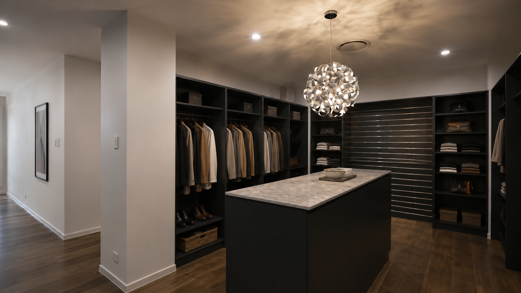 Modern walk-in closet with dark wood shelving, hanging clothes, a central island, and a chandelier
